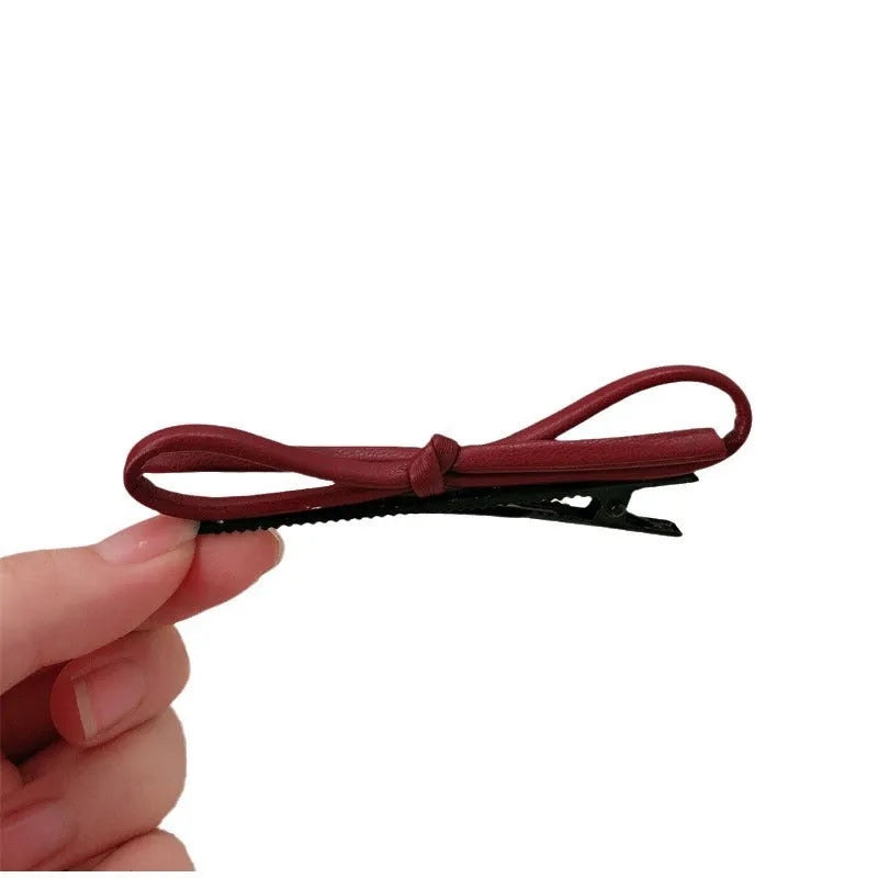 Wine red leather bow hair barrette on white background showing handmade construction
