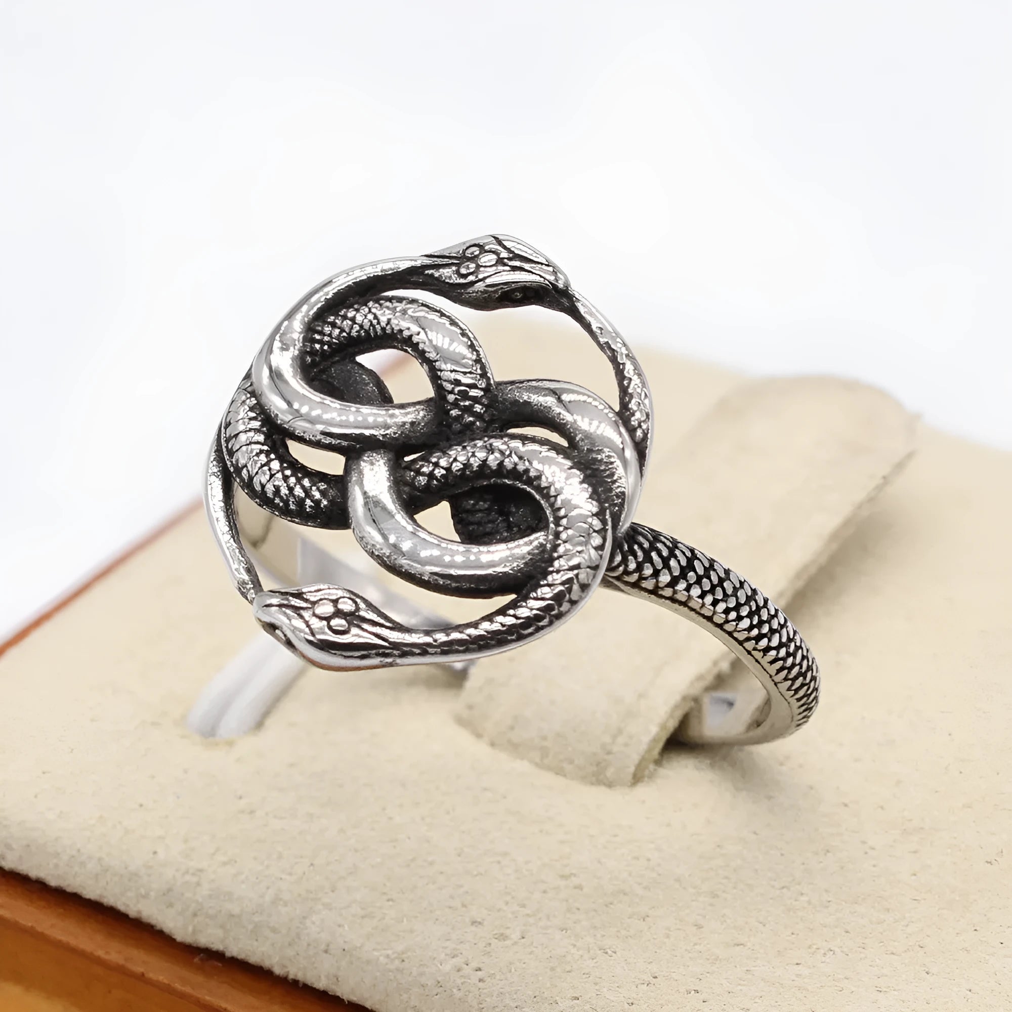 Close-up of a titanium steel double snake ring in retro style on a grey background