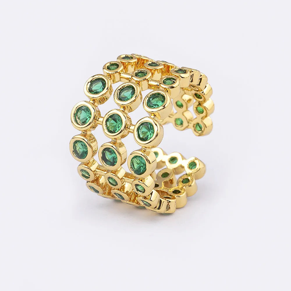 Close-up of a wide, layered copper ring with 18K gold plating and green zircon stones.