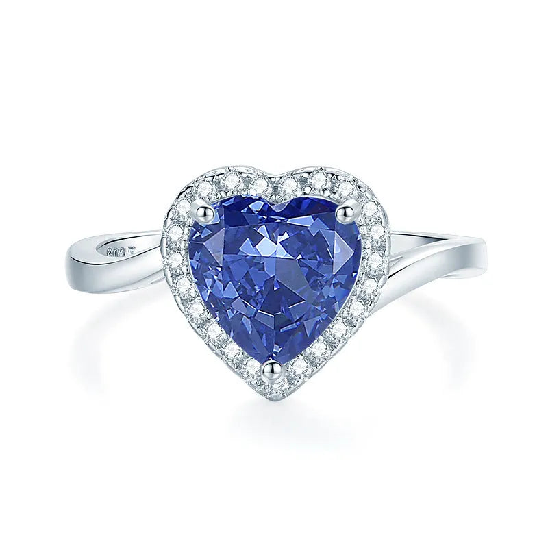 Close-up of a sterling silver heart-shaped ring with a floral-cut blue zircon stone.