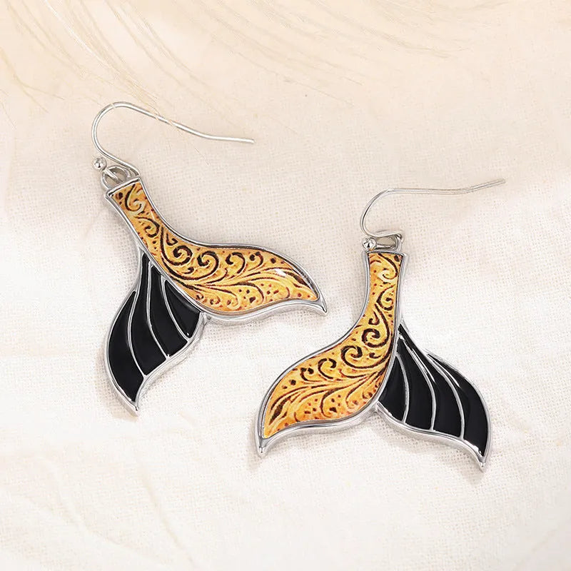 A pair of women's retro-style fishtail earrings with a whale decoration in white gold colour.