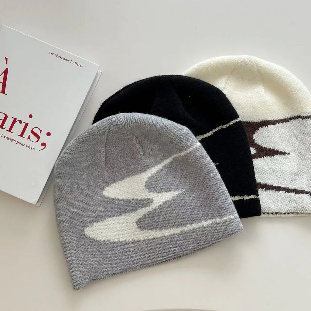 Acrylic knit beanie hat in black on a grey background, showing ribbed texture.