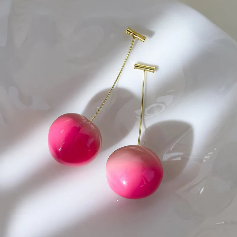 A pair of acrylic peach-shaped earrings with copper posts, shown in small and large size options.