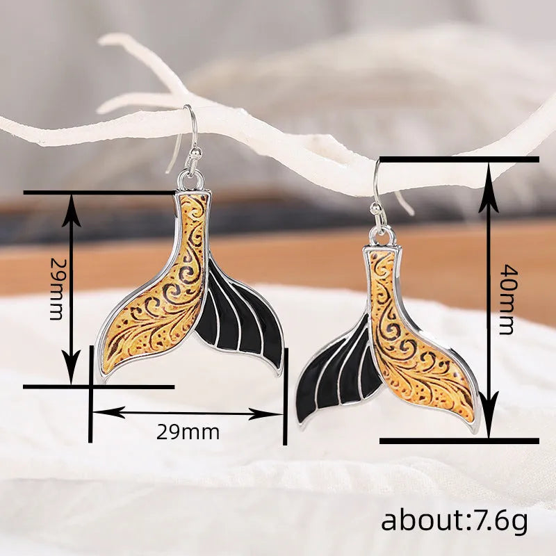 A pair of women's retro-style fishtail earrings with a whale decoration in white gold colour.