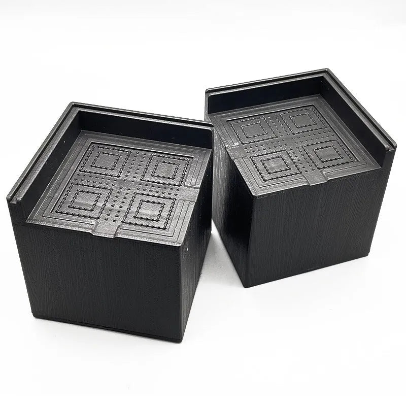 Four black plastic furniture risers or feet for beds and sofas