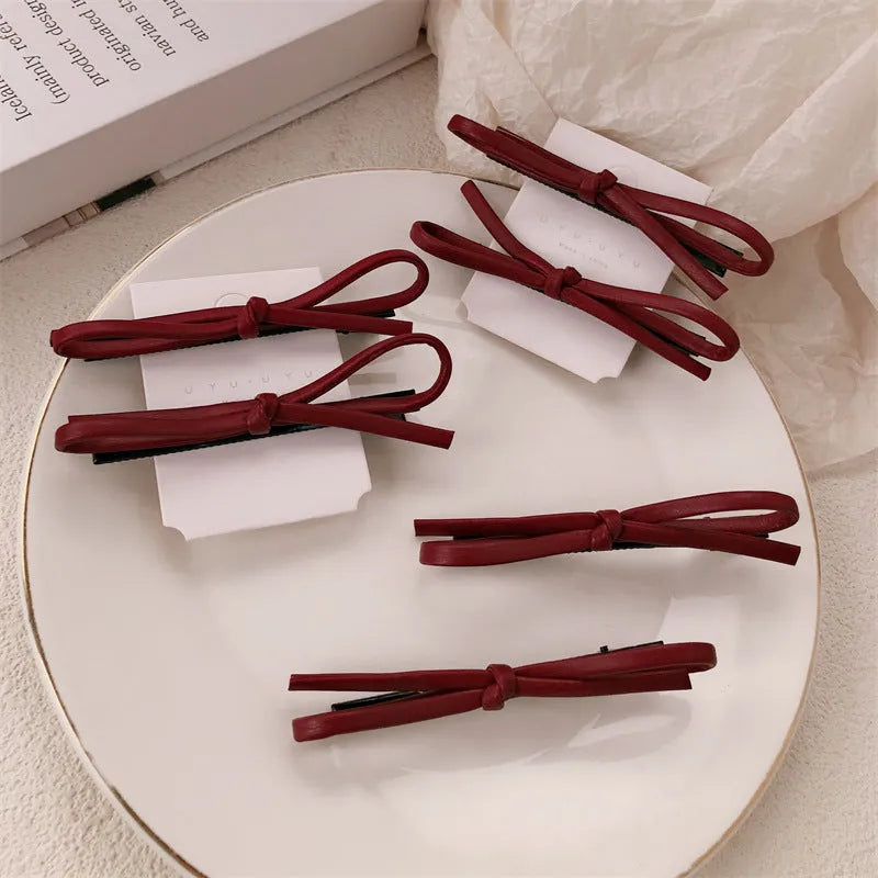 Wine red leather bow hair barrette on white background showing handmade construction