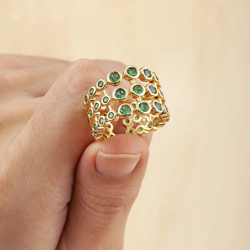 Close-up of a wide, layered copper ring with 18K gold plating and green zircon stones.