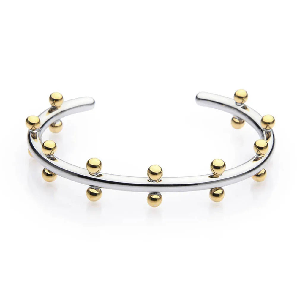 Close-up of a C-shaped stainless steel bean bead with textured rivet design, next to an alloy bracelet.