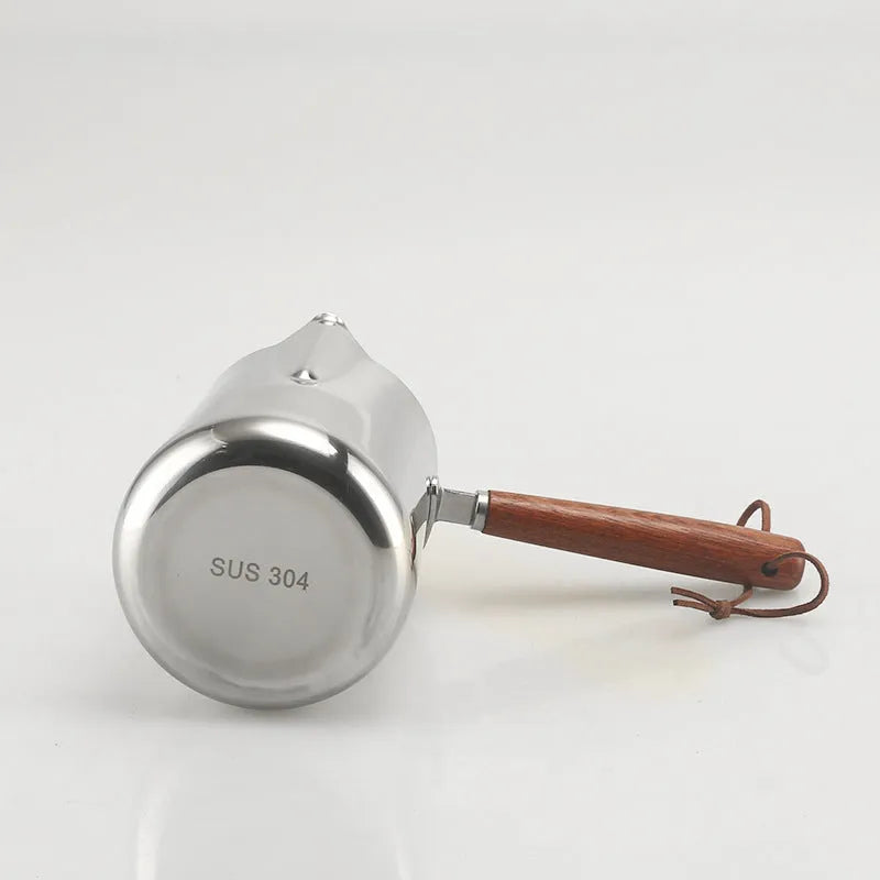 Stainless steel milk frothing pitcher with interior measurement scale and wooden handle