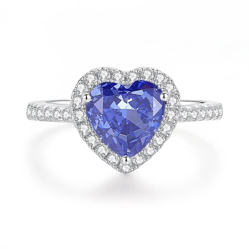 Close-up of a sterling silver heart-shaped ring with a floral-cut blue zircon stone.