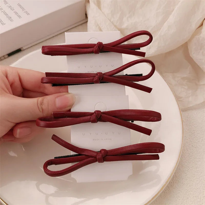 Wine red leather bow hair barrette on white background showing handmade construction