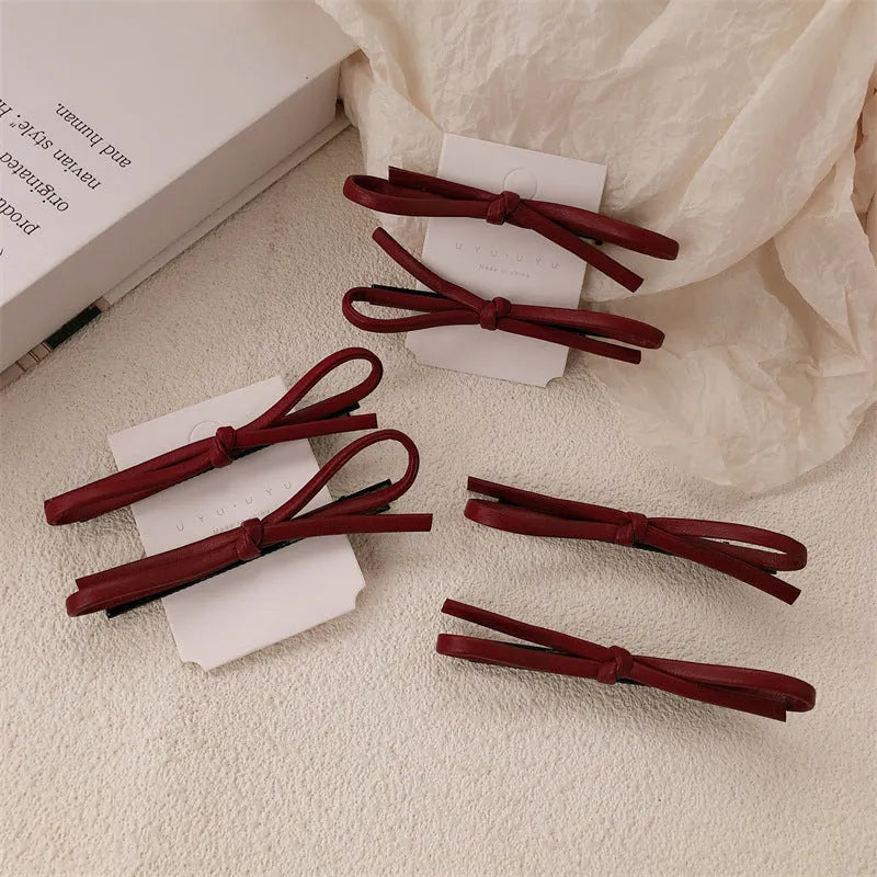 Wine red leather bow hair barrette on white background showing handmade construction