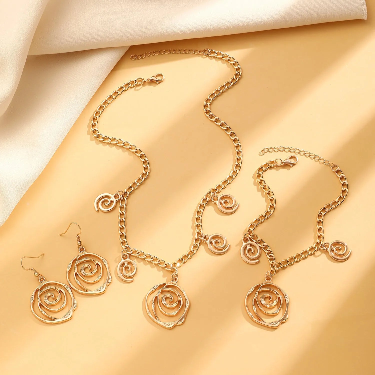 Spiral donut jewellery set showing necklace, bracelet, and earrings in geometric circle design with gold electroplated finish