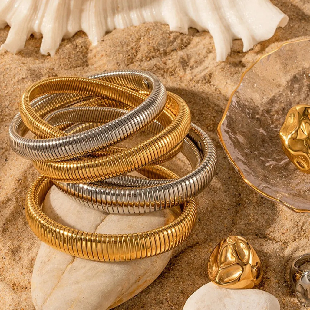 Close-up of a women's titanium steel bracelet with an exaggerated vertical stripe ring elastic design in a gold finish.