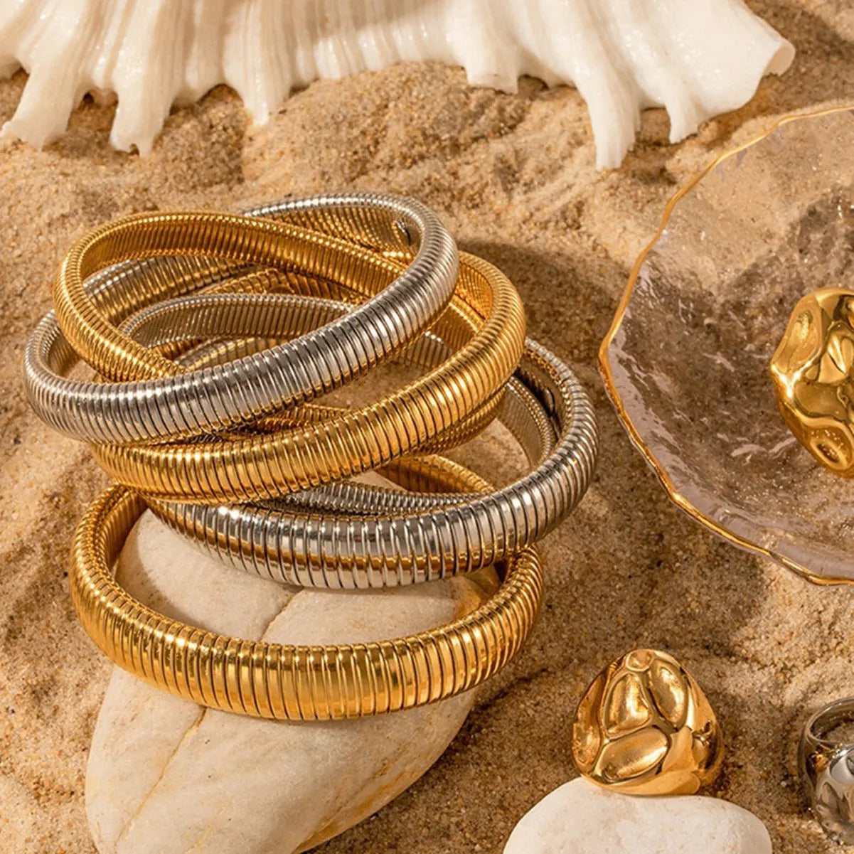 Close-up of a women's titanium steel bracelet with an exaggerated vertical stripe ring elastic design in a gold finish.