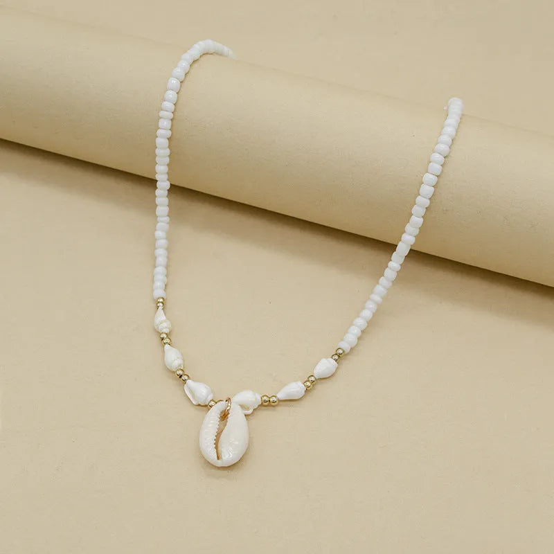 White necklace with a natural shell-shaped mother of pearl pendant on a metal chain.