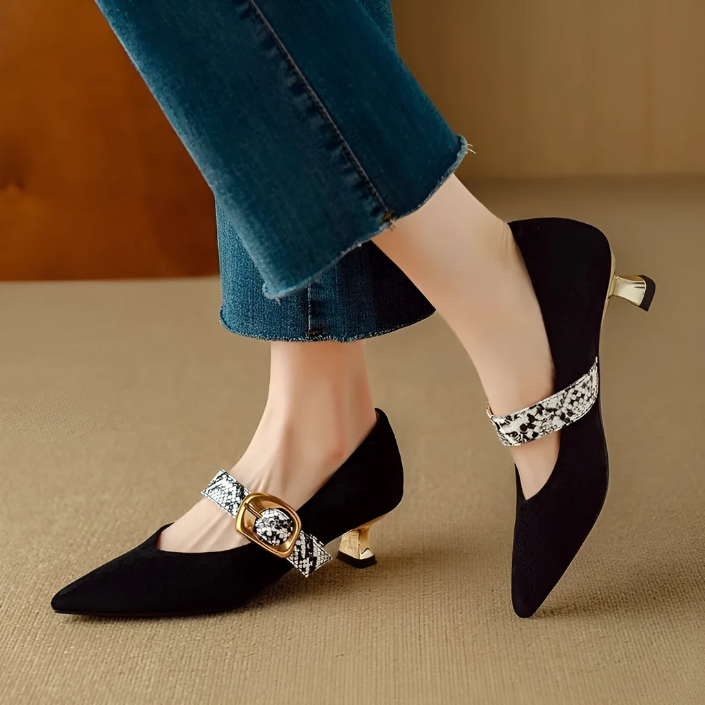 Women's black low-cut pointed stiletto heels with a silver buckle fastening on the ankle strap.