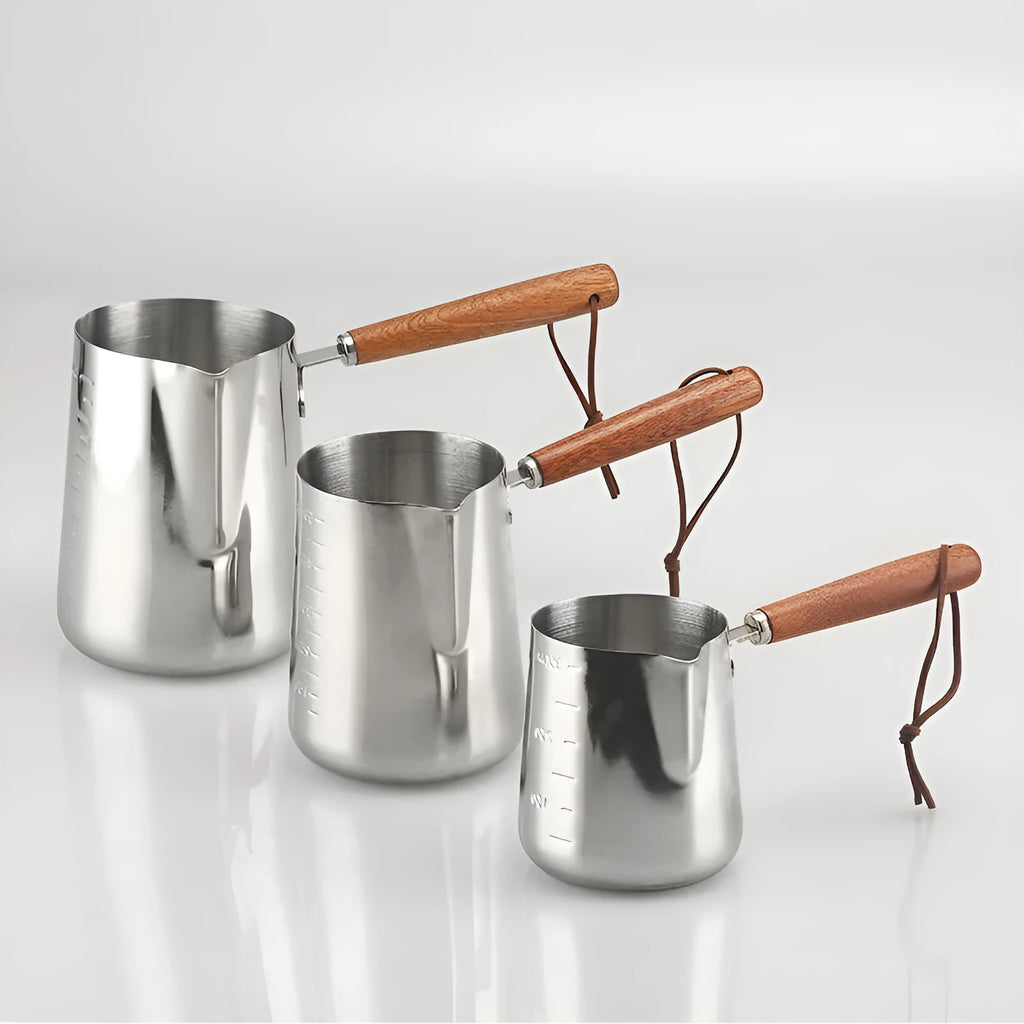 Stainless steel milk frothing pitcher with interior measurement scale and wooden handle