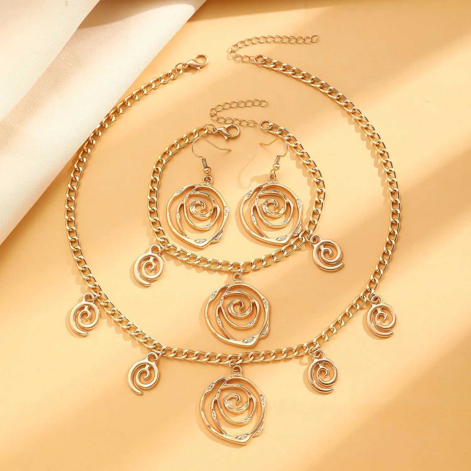 Spiral donut jewellery set showing necklace, bracelet, and earrings in geometric circle design with gold electroplated finish