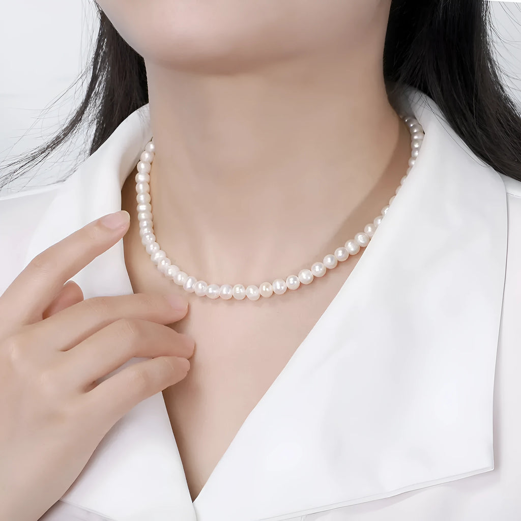 Women's simple sterling silver necklace with round freshwater pearls on an adjustable chain.