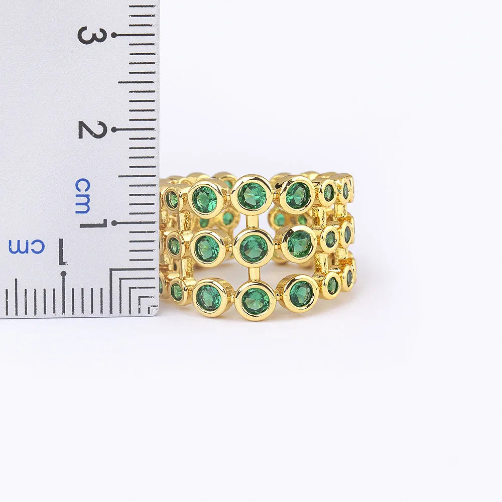 Close-up of a wide, layered copper ring with 18K gold plating and green zircon stones.