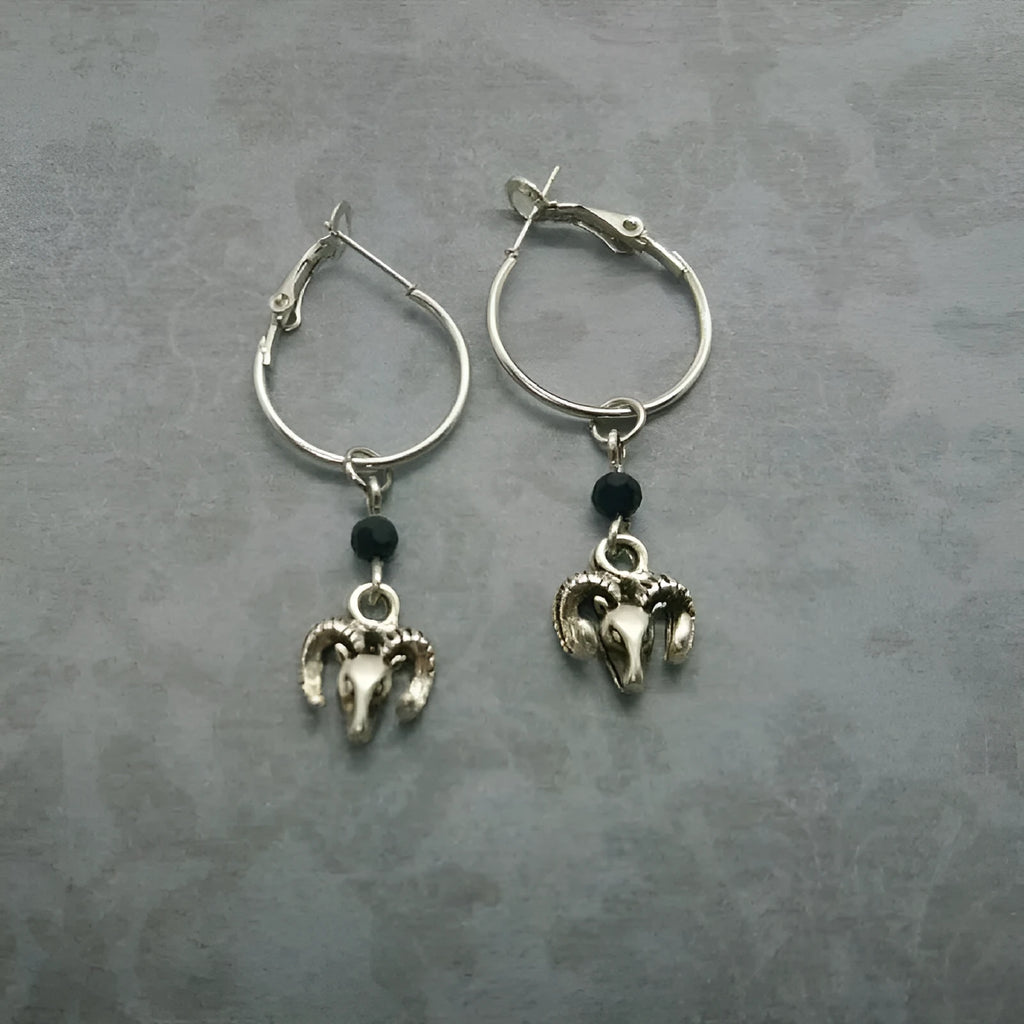A pair of silver-coloured round alloy earrings featuring a Tibetan antelope design.
