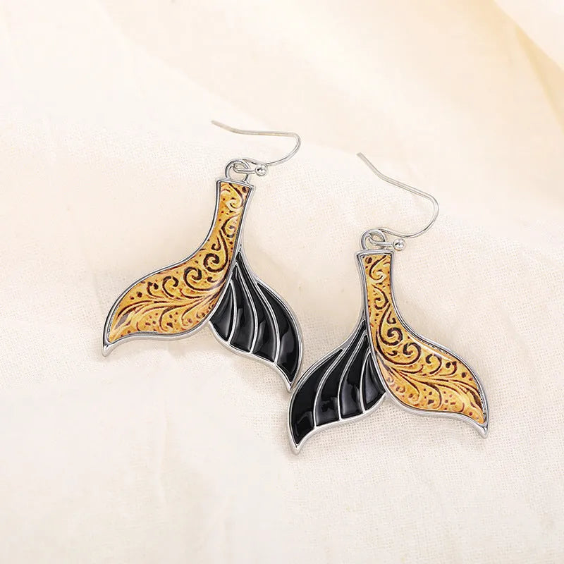 A pair of women's retro-style fishtail earrings with a whale decoration in white gold colour.