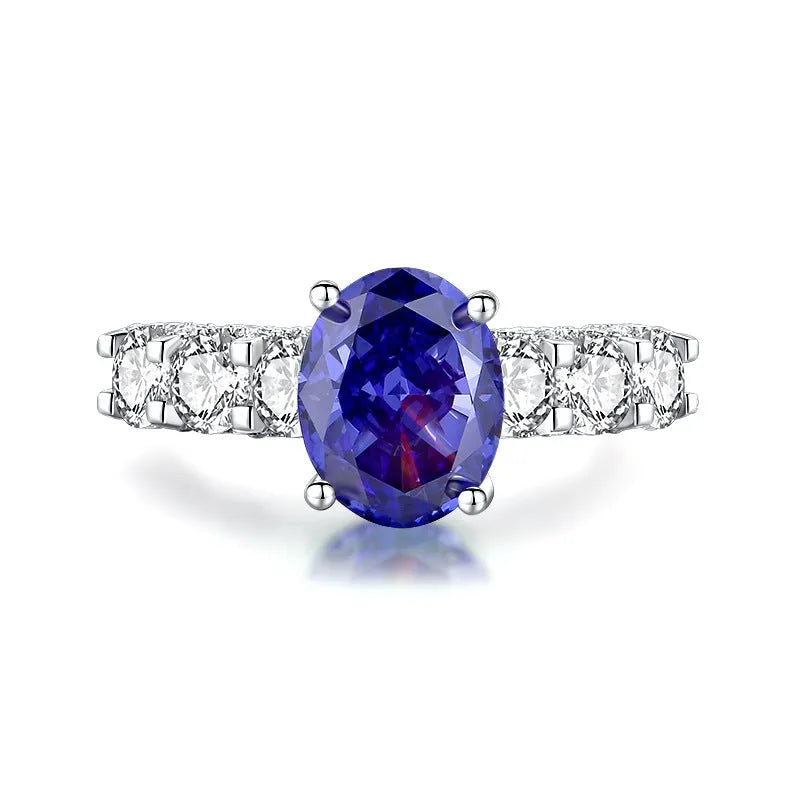 Close-up of a sterling silver heart-shaped ring with a floral-cut blue zircon stone.