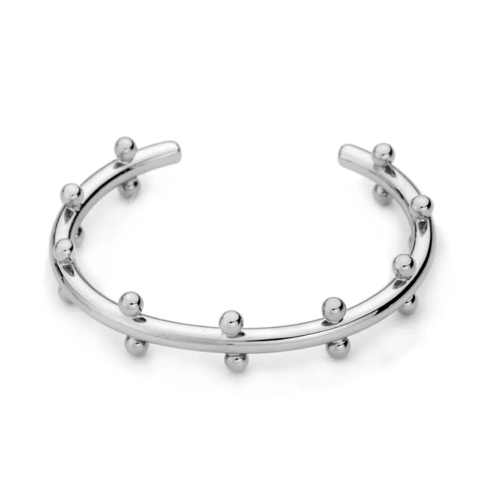 Close-up of a C-shaped stainless steel bean bead with textured rivet design, next to an alloy bracelet.