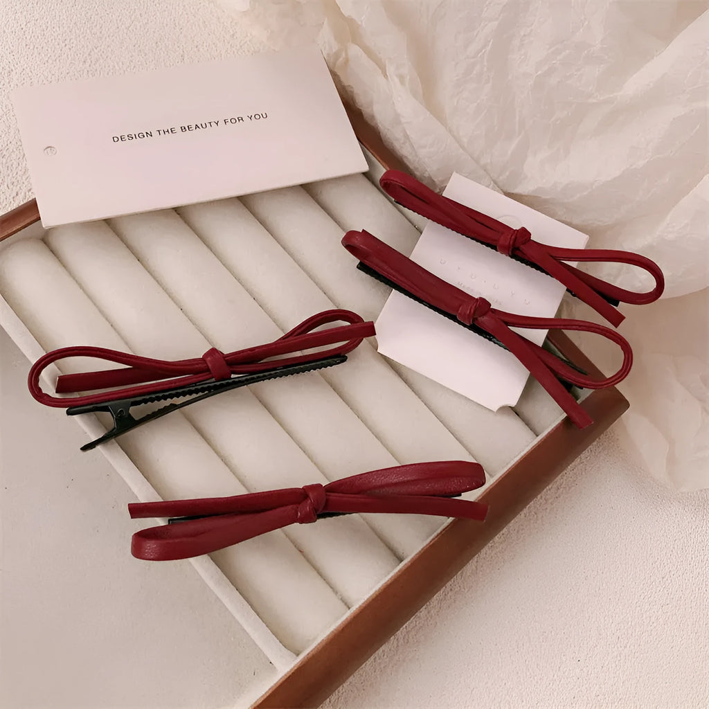 Wine red leather bow hair barrette on white background showing handmade construction