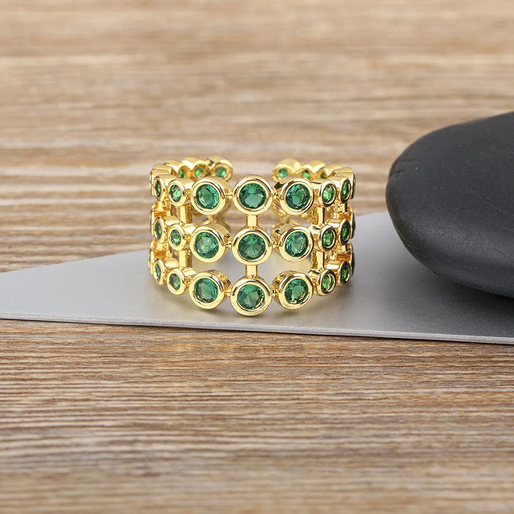 Close-up of a wide, layered copper ring with 18K gold plating and green zircon stones.