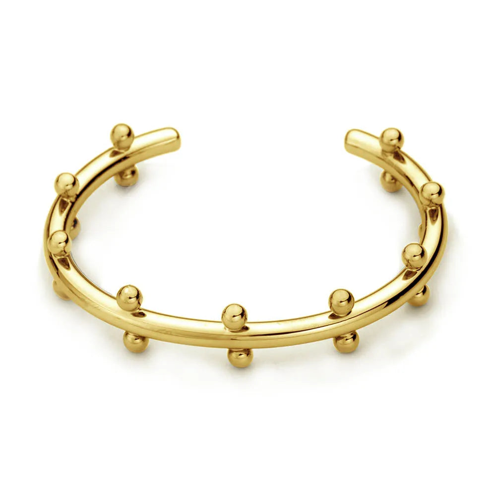 Close-up of a C-shaped stainless steel bean bead with textured rivet design, next to an alloy bracelet.