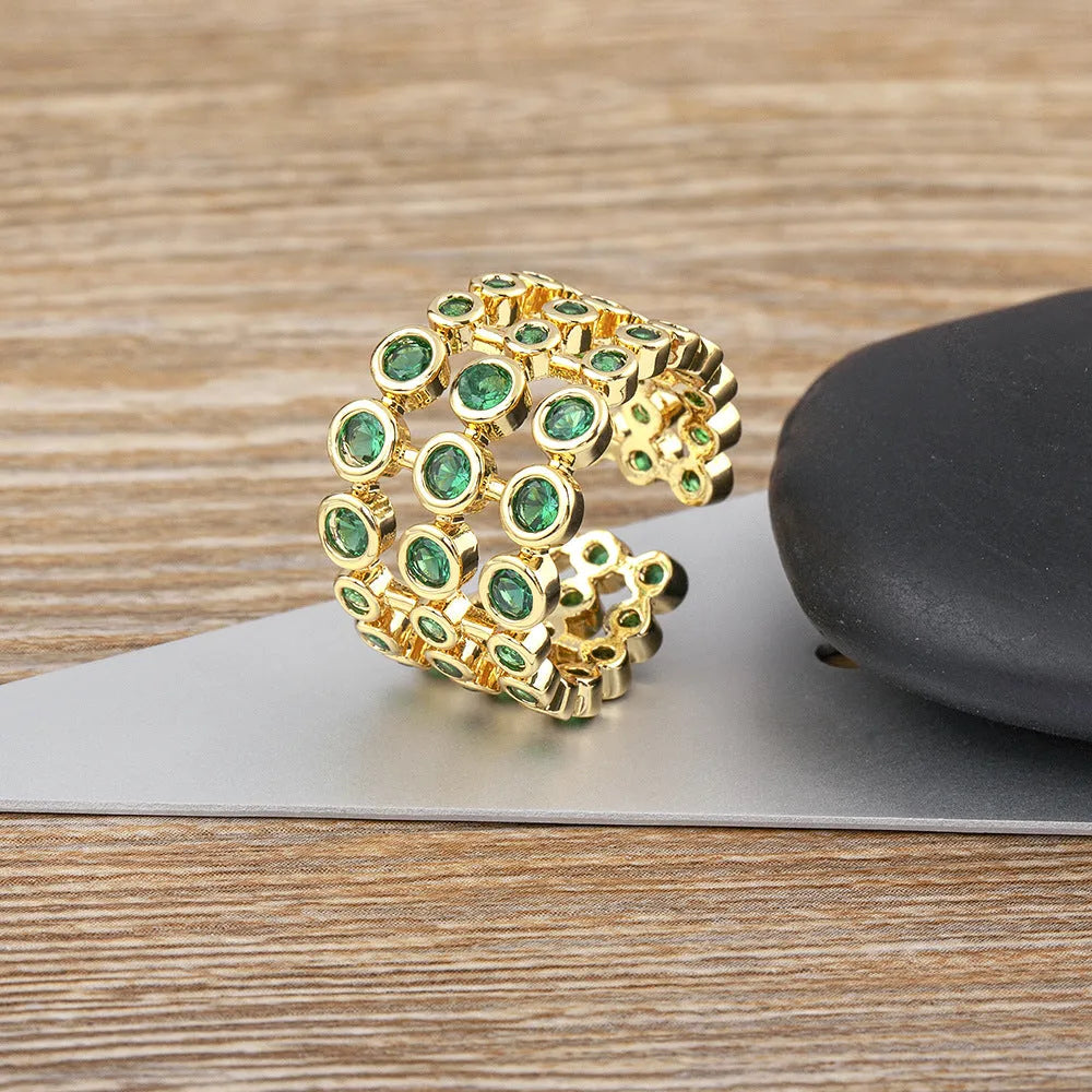 Close-up of a wide, layered copper ring with 18K gold plating and green zircon stones.
