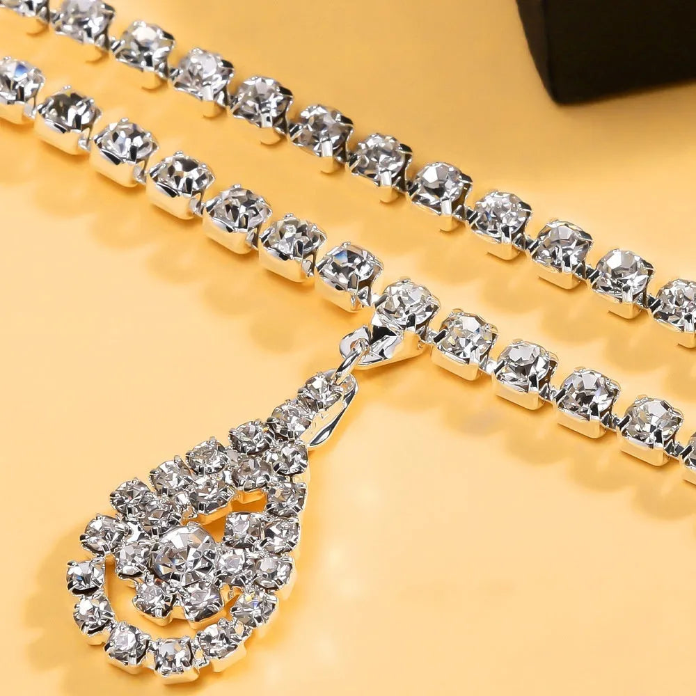 Gold coloured waist chain with a sparkling rhinestone water drop pendant and tassel details.