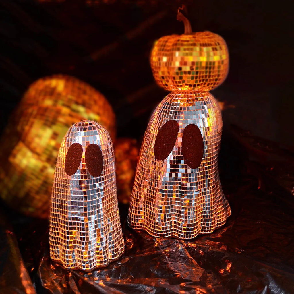Silver glass ghost decoration with mosaic mirror patch on a desktop for Halloween.