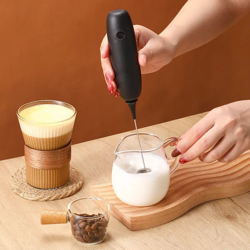Black and white handheld electric milk frother with modern design for coffee preparation