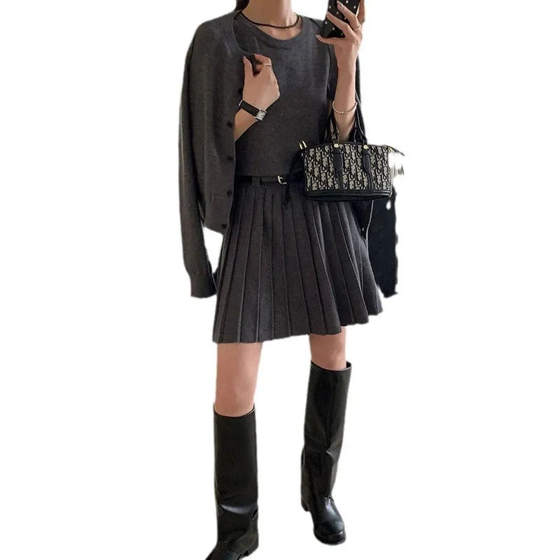 Women's black knitted two-piece set showing vest skirt with belt and long-sleeved cardigan with 3D pattern