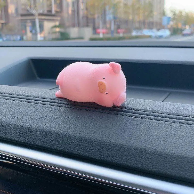 A cute resin cartoon pig figurine car dashboard decoration on a grey background.