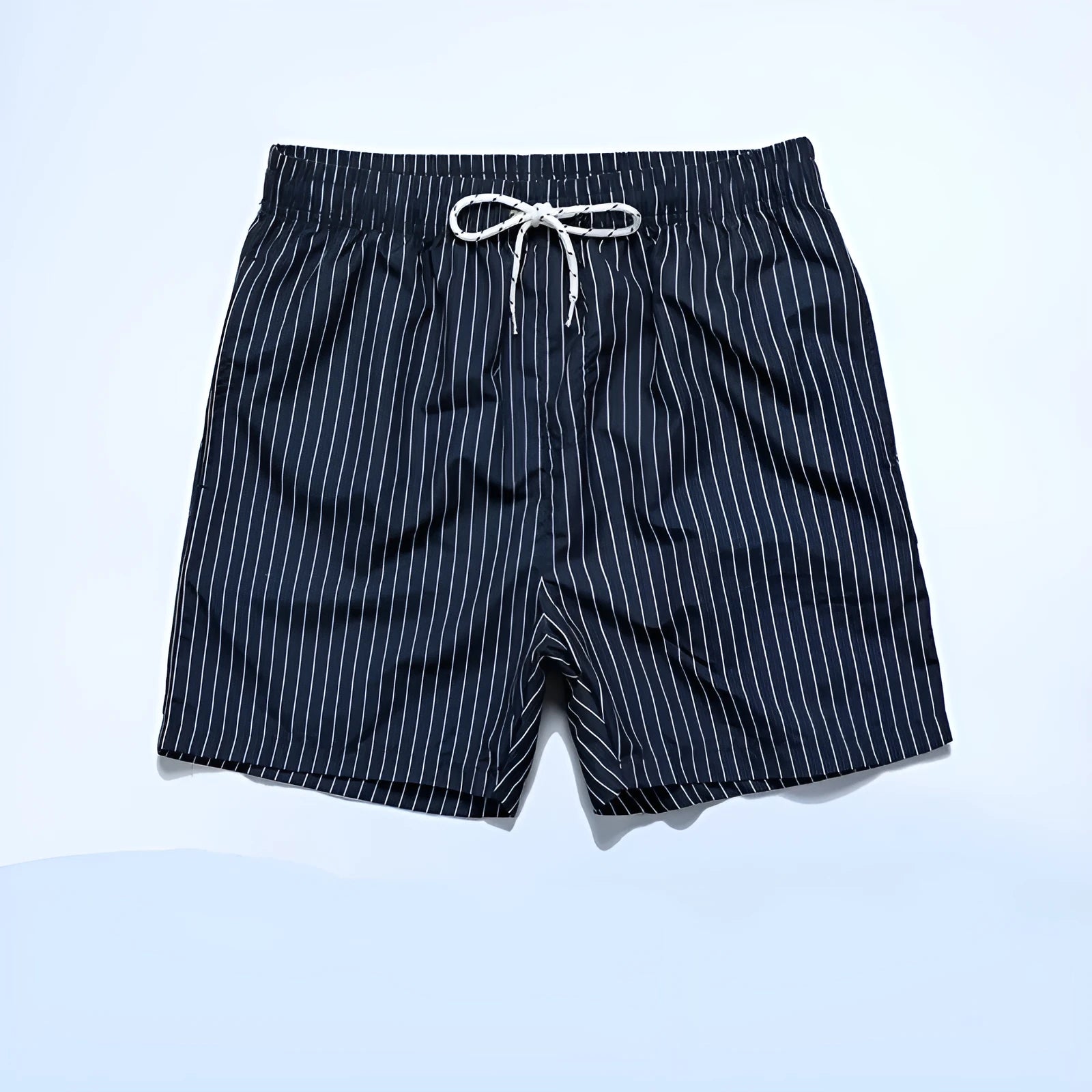 A man wearing grey striped polyester beach shorts with a straight leg opening, shown on a beach.