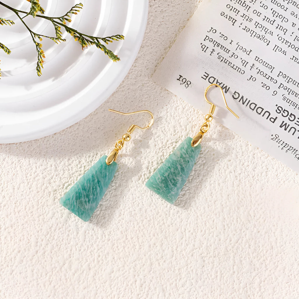 A pair of trapezoid-shaped rough amazonite earrings on a gold and silver background.