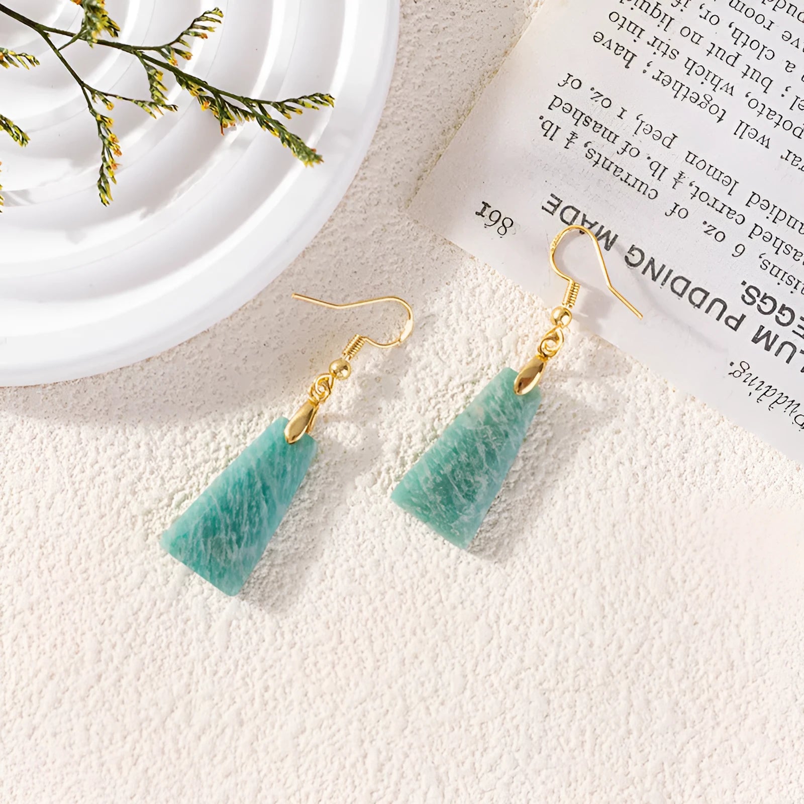 A pair of trapezoid-shaped rough amazonite earrings on a gold and silver background.