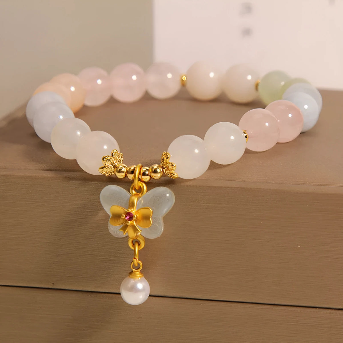 Women's adjustable crystal bracelet with a colourful morganite butterfly pendant on a white background.