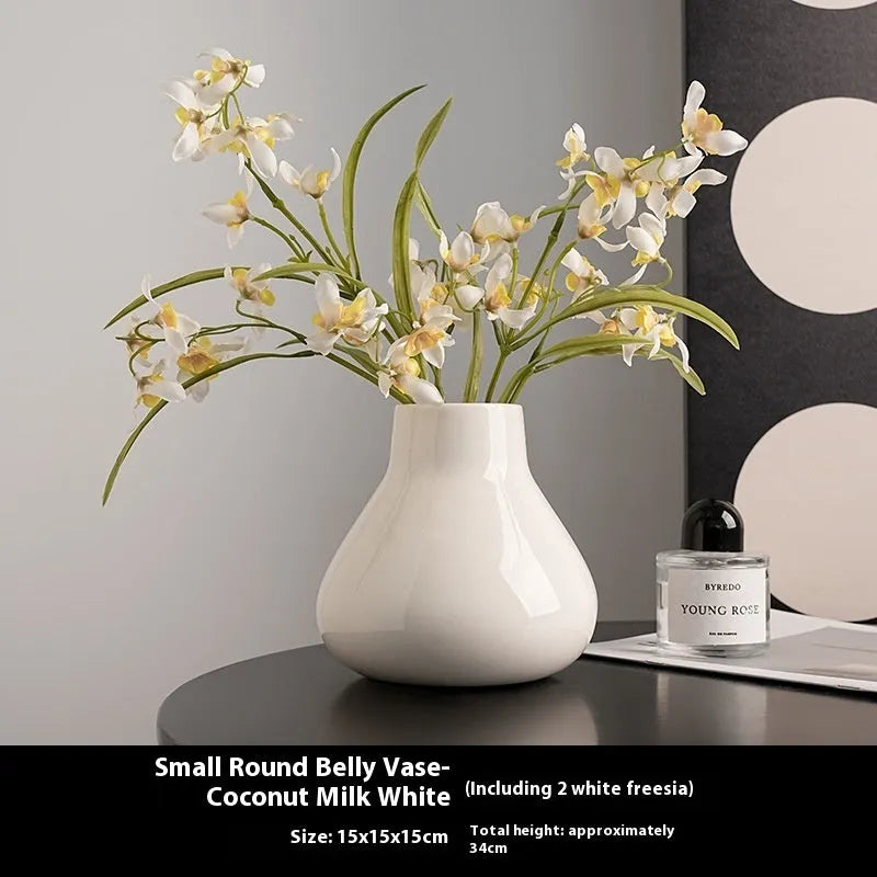 Black ceramic modern vase with white artificial orchid stems on wooden table