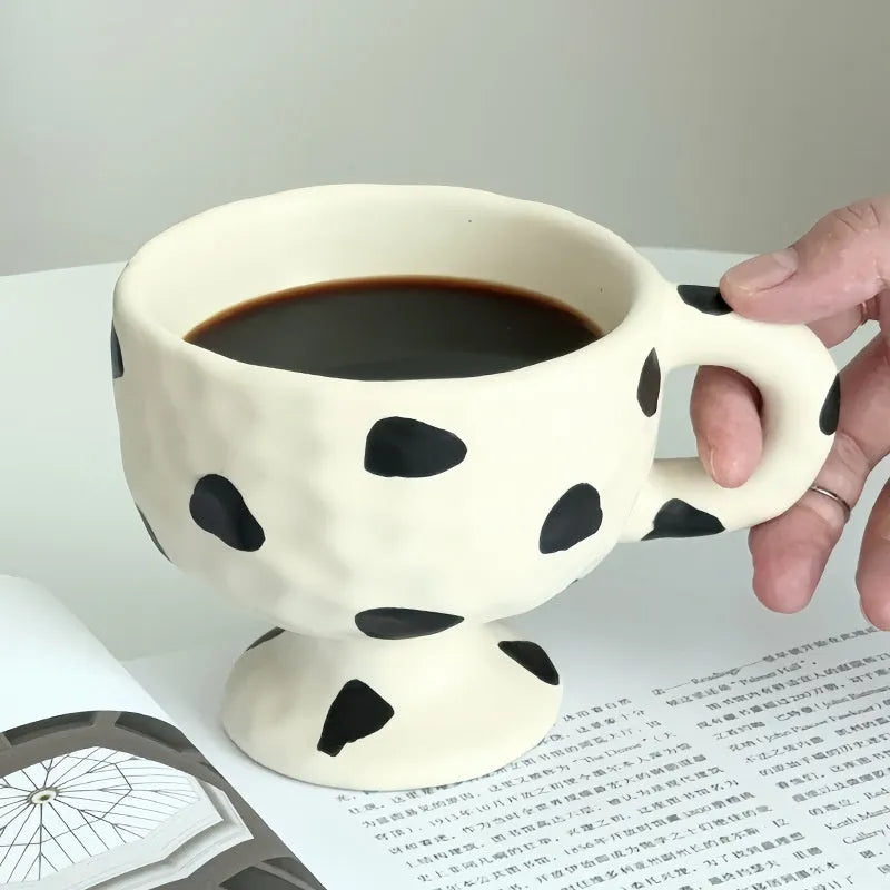 Hand-pinched irregular shaped solid colour ceramic mug on a table, showing its unique form and modern simplicity design.
