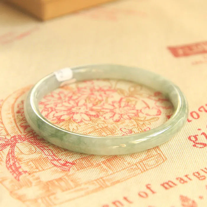 Green handmade geometric jade waxy bracelet with adjustable sizing on a wrist.