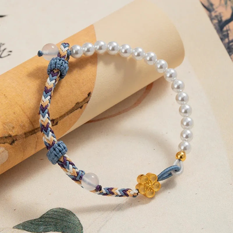Peach-coloured adjustable cord bracelet with Chinese flower weaving and pearl details.