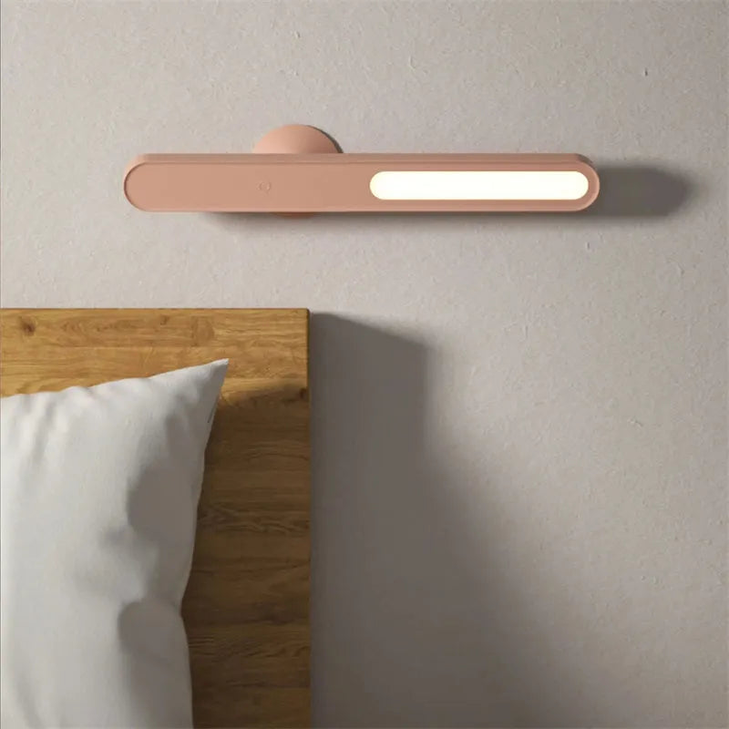 Geometric shaped white desk lamp with a magnetic base on a wooden table next to a book.