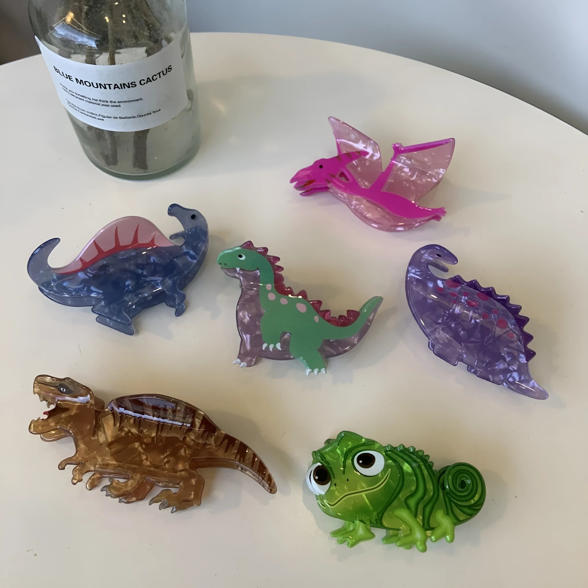 Colourful dinosaur-themed acrylic jaw hair clip showing multiple design options
