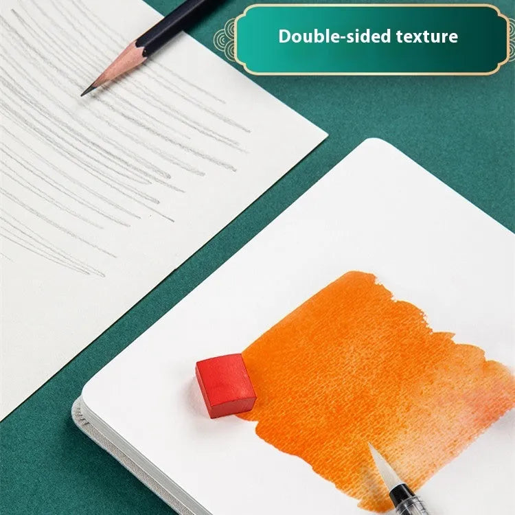 Feiluniao handmade fabric watercolour notebook open on a table with paints, showing a decorative cover.