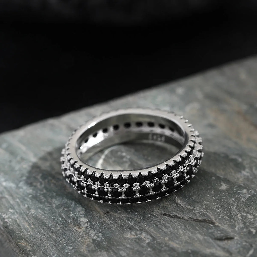 A geometric triangle ring with a zircon inlay, shown in a choice of platinum, yellow gold, or white and black colour.